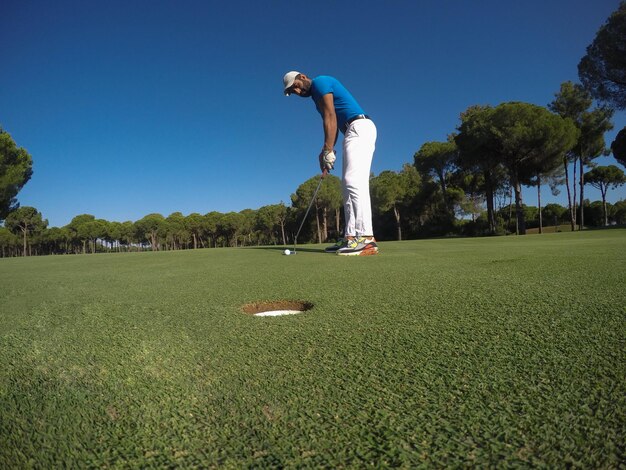 giocatore di golf che colpisce colpo con autista in corso in una bella giornata di sole