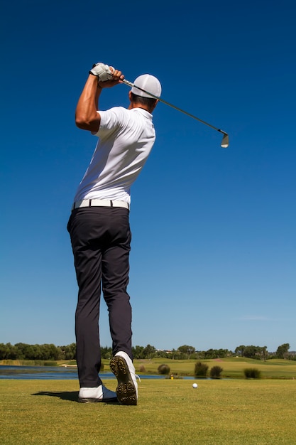 Giocatore di golf che colpisce una pallina da golf in un bellissimo campo da golf.