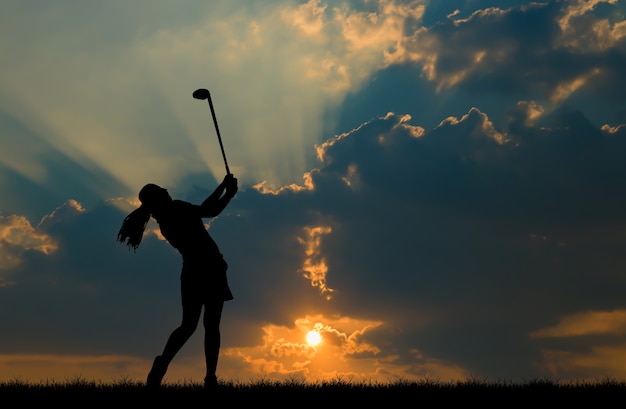 giocatore di golf della siluetta che gioca golf durante il bello tramonto