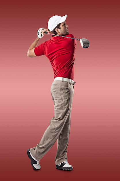 Giocatore di golf in una camicia rossa che fa un'oscillazione, su una priorità bassa rossa.
