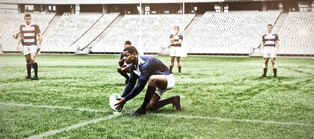 Giocatore di rugby maschio afroamericano che posiziona la palla di rugby su un supporto nello stadio