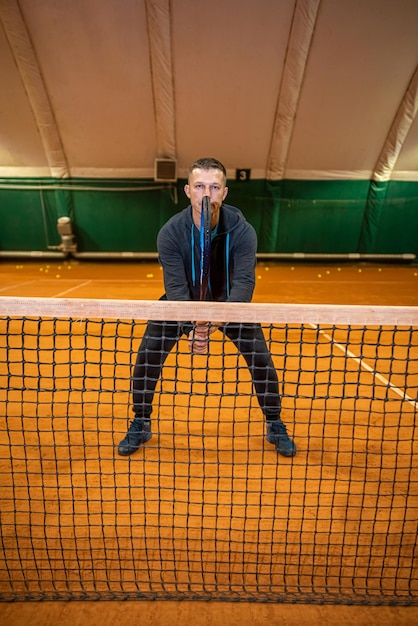 Giocatore di tennis atleta agile che gioca a tennis su un campo coperto