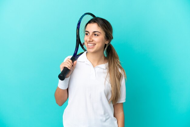 Giocatore di tennis della giovane donna isolato su fondo blu che guarda side