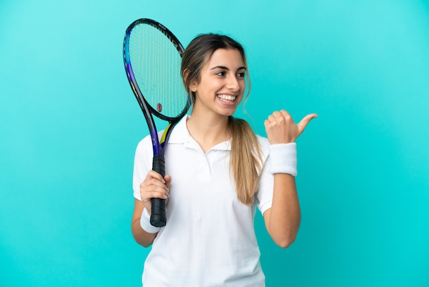 Giocatore di tennis della giovane donna isolato su fondo blu che indica il lato per presentare un prodotto