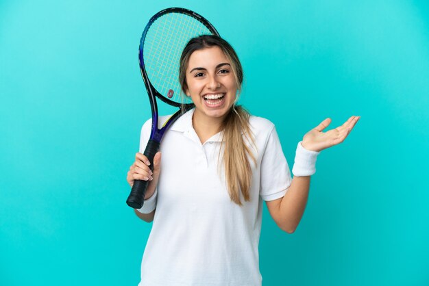 Giocatore di tennis della giovane donna isolato su fondo blu con l'espressione facciale scioccata