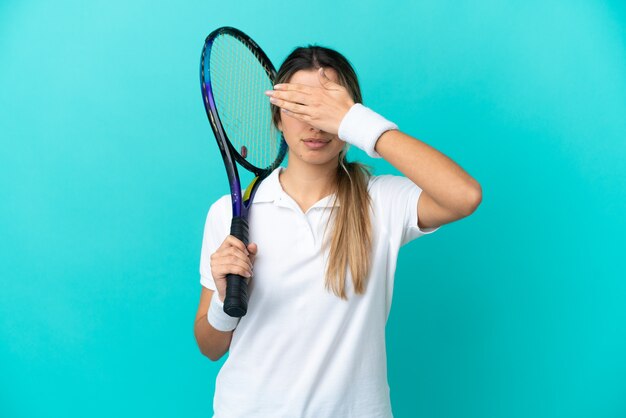 Giocatore di tennis della giovane donna isolato su priorità bassa blu che copre gli occhi con le mani. Non voglio vedere qualcosa