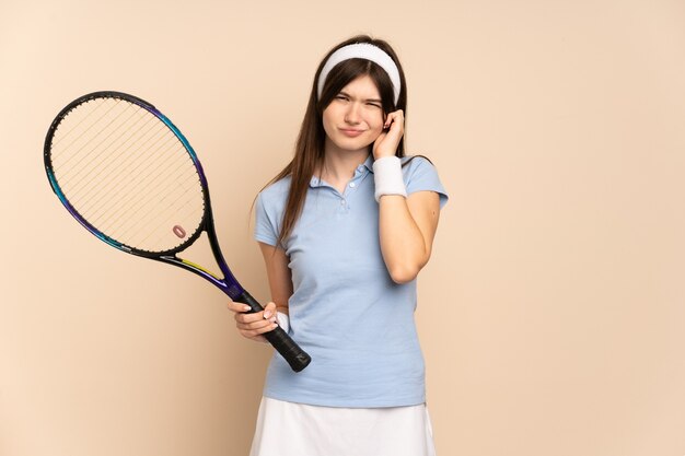 Giocatore di tennis della ragazza sopra la parete isolata frustrata e che copre le orecchie