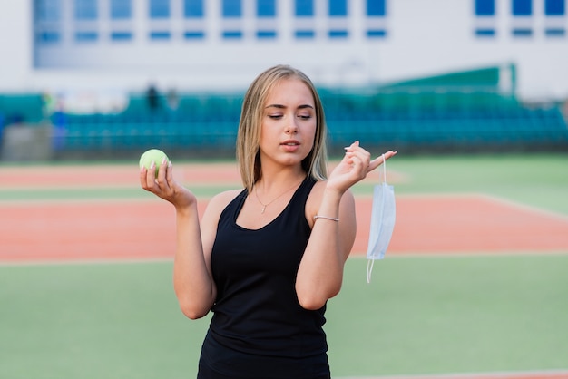 Giocatore di tennis femminile che gioca con la maschera protettiva sulla corte