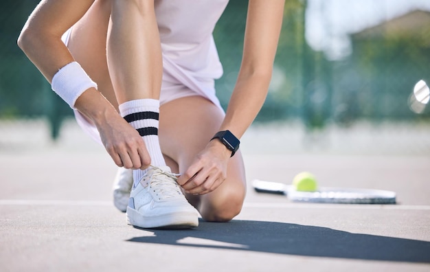 Giocatore di tennis femminile che lega i lacci delle scarpe prima della partita sul campo sportivo all'aperto Donna sportiva attiva che si prepara per l'allenamento per divertenti esercizi estivi e uno stile di vita sano e benessere