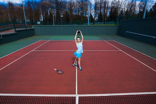 Giocatore di tennis in abito bianco e tacchi con racchetta da tennis sul campo