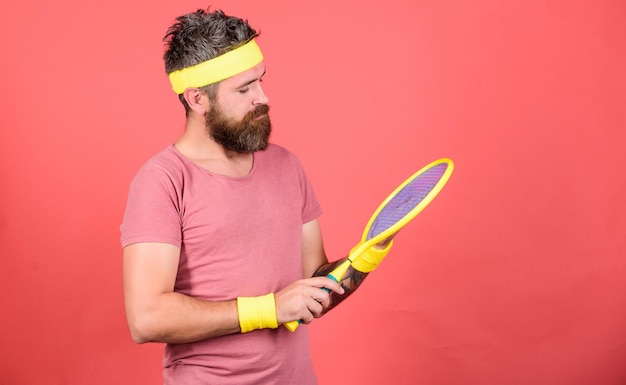 Giocatore di tennis moda retrò Tennis sport e intrattenimento Pantaloni a vita bassa atleta tenere in mano la racchetta da tennis sfondo rosso Giocare a tennis per divertimento Uomo hipster con la barba indossare abbigliamento sportivo Raggiungere di nuovo la parte superiore