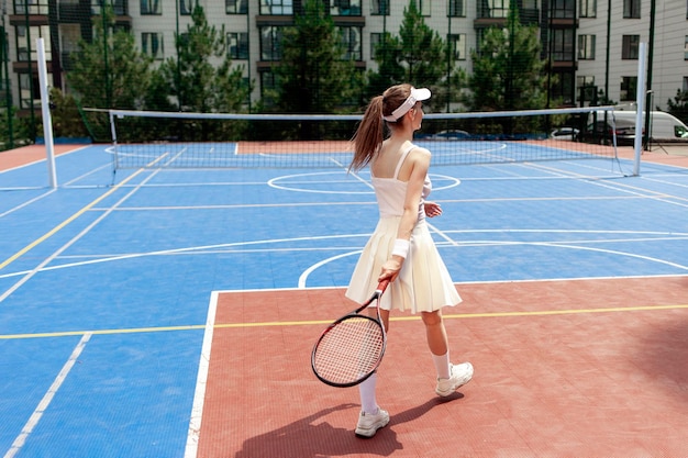 giocatore di tennis ragazza in uniforme bianca che tiene la racchetta sul campo da tennis atleta femminile che gioca a tennis