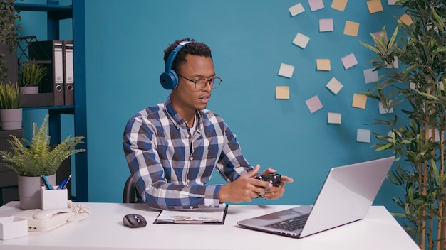 Giocatore frustrato che perde videogiochi online su console, gioca con il controller su laptop e cuffie. Il giocatore si sente deluso dal gameplay perso sul computer con il joystick.