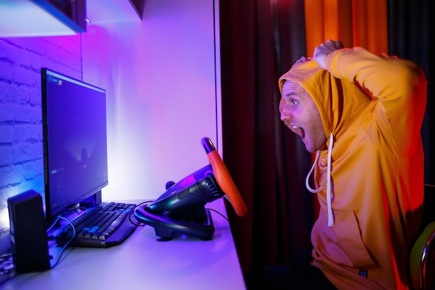 Giocatore maschio che gioca a giochi di corse sul computer Usa il volante Gioco emotivo