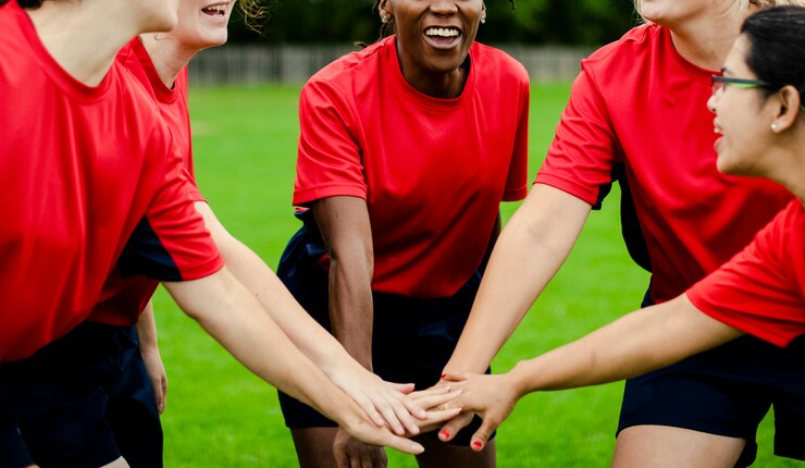 Foto giocatori di rugby femminile accatastando le mani insieme