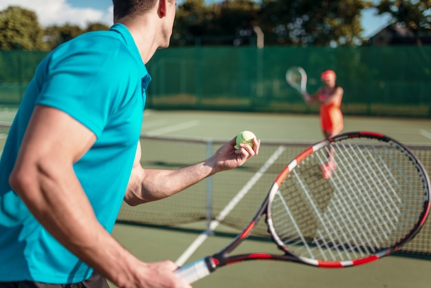 Giocatori di sesso maschile e femminile con le racchette sul campo da tennis all'aperto.