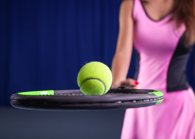 Giocatrice che tiene in mano una racchetta da tennis e una palla