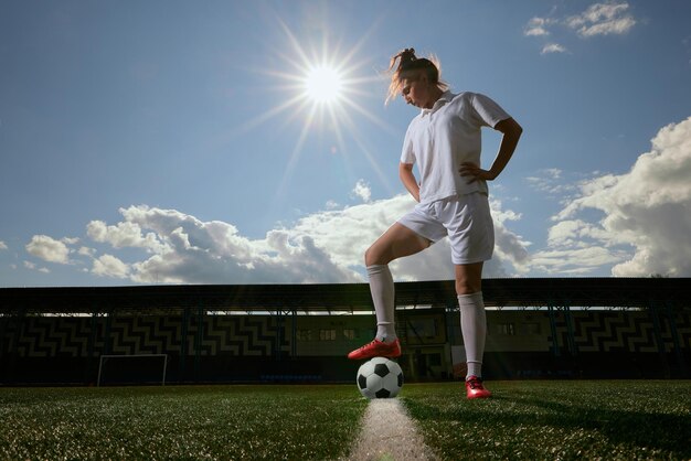 Giocatrice di calcio con una palla da calcio sul campo da calcio concetto di donne professioniste