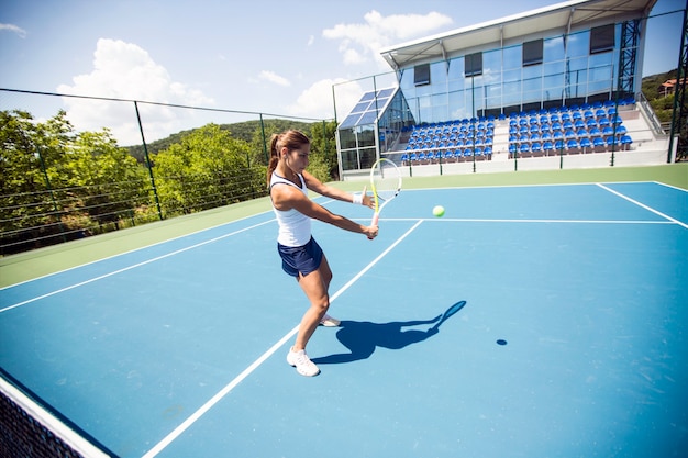 Giocatrice di tennis che esegue un drop shot su un bel campo blu