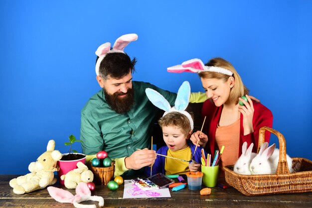 Giocattoli a sorpresa di uova madre padre e bambino che dipingono le uova di Pasqua