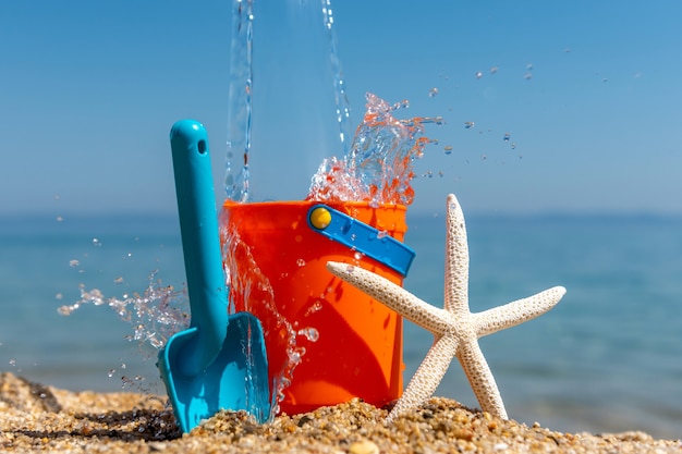 Giocattoli da spiaggia per bambini secchi, paletta e stelle marine sulla sabbia