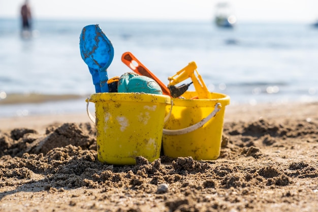 Giocattoli da spiaggia per bambini secchi vanga e pala sulla sabbia in una giornata di sole