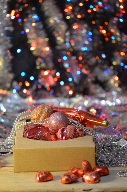 Giocattoli di decorazione di Capodanno in una scatola di cartone su uno sfondo di legno Decorazioni natalizie imballate Decorazioni di Capodanno e giocattoli in una scatola di cartone