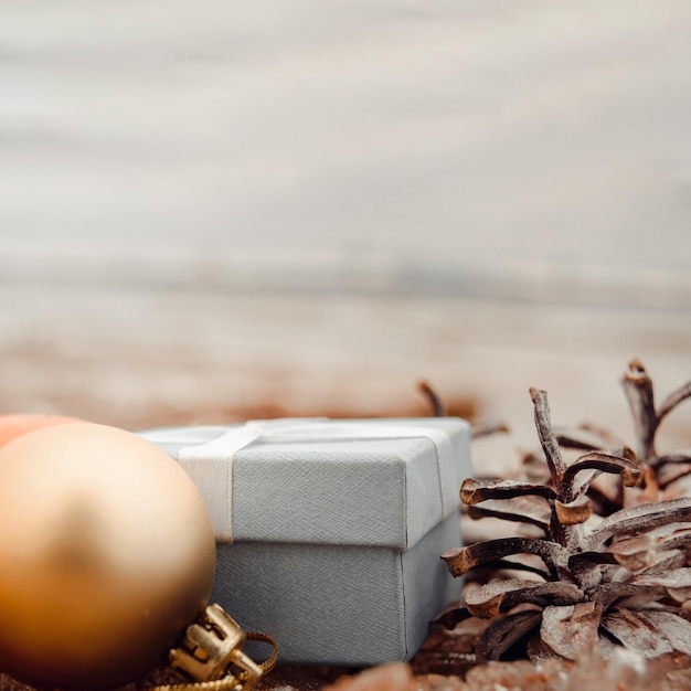 Giocattoli di Natale palline d'oro e una confezione regalo sulla spiaggia mare sfocato sullo sfondo Invito a una cartolina di Natale o di Capodanno con spazio per la copia del testo