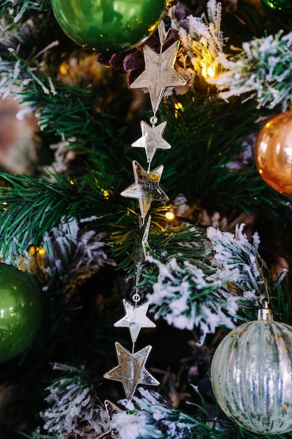 Giocattoli e ghirlanda con le stelle sull'albero di Natale da vicino