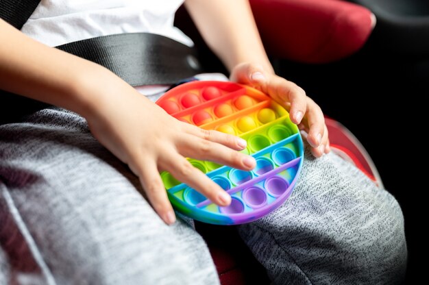 Giocattoli pop sensoriali antistress nelle mani di un bambino. un ragazzino felice gioca con un semplice giocattolo con fossette in macchina.