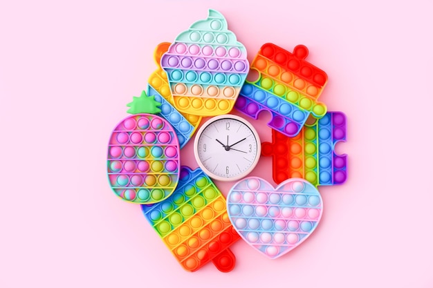 Giocattoli sensoriali antistress colorati con orologio su sfondo rosa