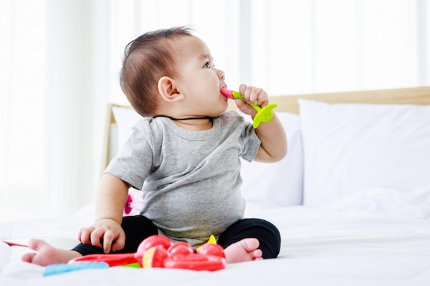 Giocattolo del bambino del gioco del bambino grazioso sul letto 8 mesi di sviluppo felice del bambino nel concetto del bambino