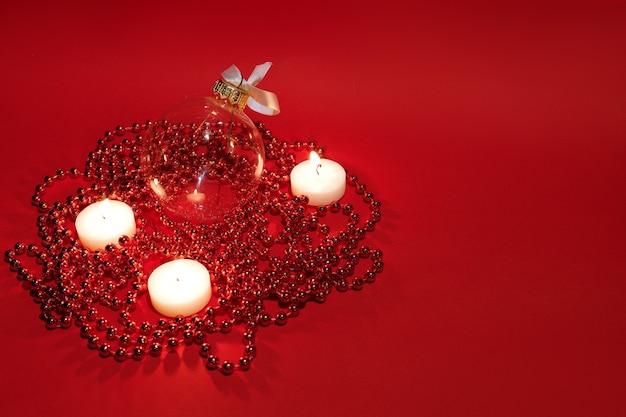 Giocattolo dell'albero di Natale e candele accese su uno sfondo di Natale rosso. spazio libero per il testo