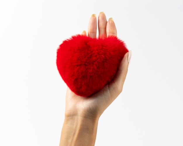 Giocattolo di pelliccia lanuginoso rosso a forma di cuore in mano di donna.