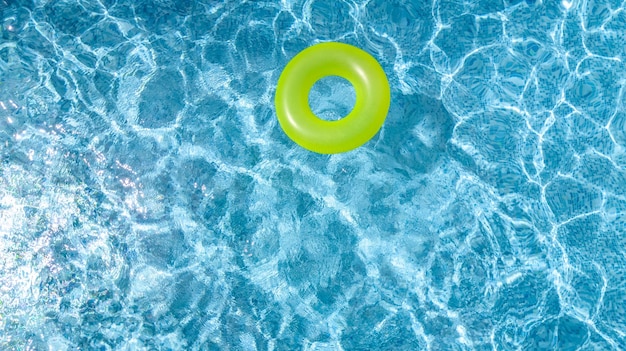 Giocattolo gonfiabile colorato della ciambella dell'anello nella vista aerea dell'acqua della piscina dall'alto