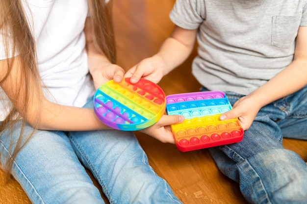 Giocattolo pop-it sensoriale anti stress nelle mani di un bambino. un piccolo bambino felice che condivide e gioca con semplici giocattoli a fossetta a casa.