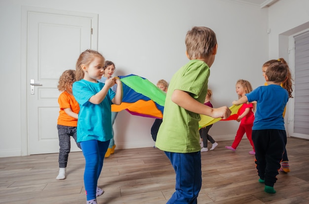 Giochi con bambini a baldacchino colorati seduti sotto il paracadute