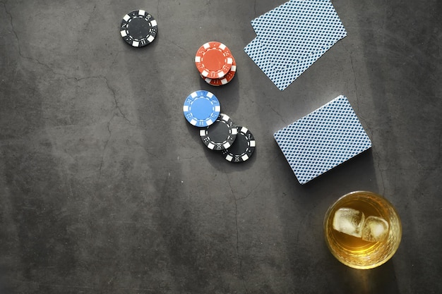 Giochi di carte per soldi. Il poker in versione Texas Holdem. Carte in mano, fiches da gioco, un mazzo di carte alcoliche in un bicchiere.