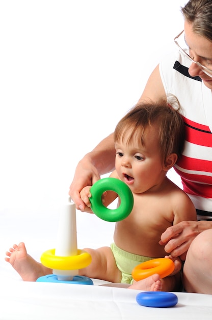 Gioco di addestramento del bambino interessato con la piramide. Piccolo bambino che gioca con il genitore e tiene l'anello del giocattolo. Ritratto su sfondo bianco isolato