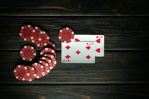 Gioco di poker con una combinazione di coppie di fiches e carte su un tavolo nero vintage in un club di poker Spazio nero gratuito per le pubblicità