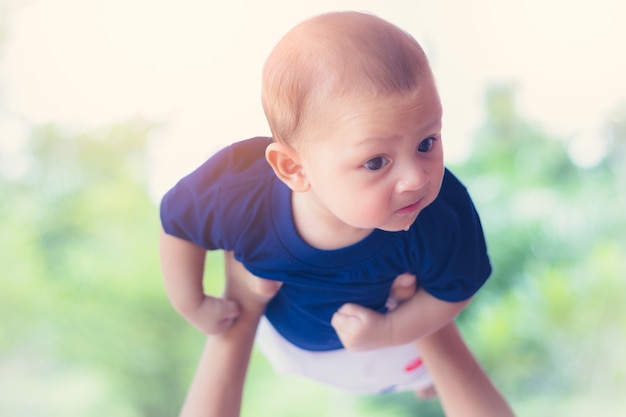 Gioco felice del bambino che vola sulla mano della madre