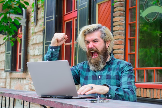 Gioco online vincente online uomo eccitato con laptop all'aperto lavoro online lavoro digitale freelance