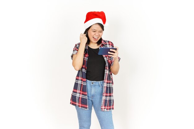 Gioco su smartphone di una bella donna asiatica che indossa una camicia a quadri rossa e un cappello da Babbo Natale