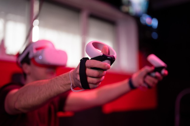 Gioco Vr e giocatore di realtà virtuale uomo divertimento giocando su simulazione futuristica videogioco di ripresa in occhiali 3d e joystick pistola nella sala vr di intrattenimento con tecnologia innovativa e luce al neon