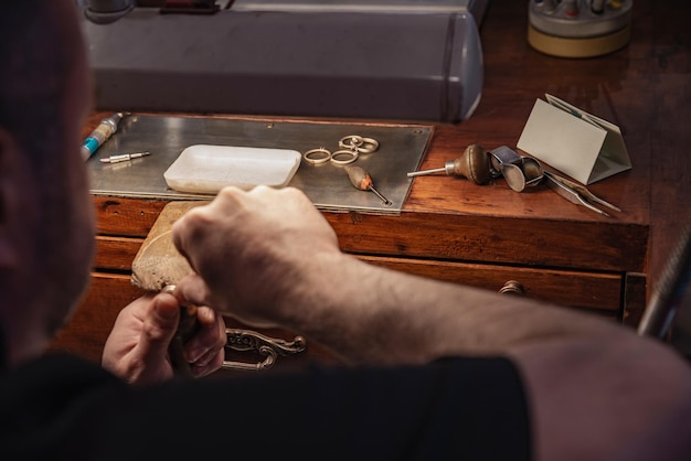 Gioielliere che lavora alla creazione di un anello su un tavolo di legno