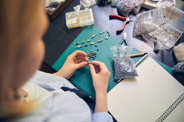 Gioielliere qualificato che utilizza filo di perline durante la creazione di una collana alla moda