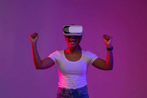 Gioiosa donna afroamericana che indossa l'auricolare vr che celebra la vittoria nel videogioco