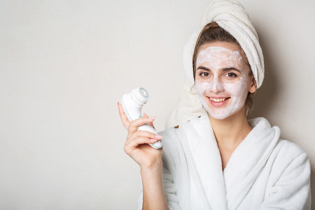 Gioiosa donna bruna in posa con maschera crema idratante e detergente per il viso. Spazio per il testo