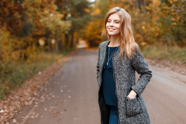 Gioiosa piuttosto bella giovane donna con cappotto grigio alla moda