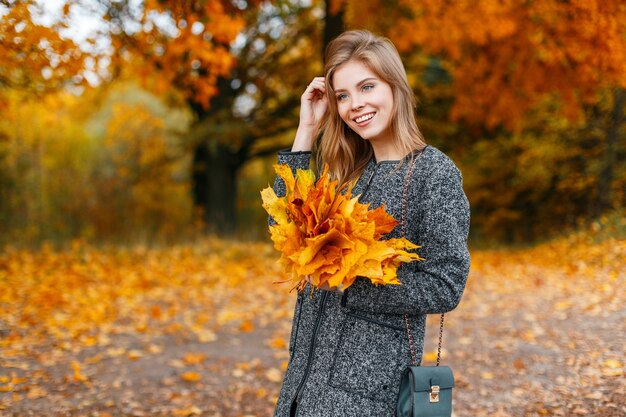 Gioiosa piuttosto bella giovane donna con cappotto grigio alla moda